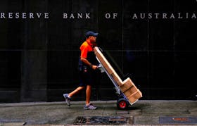 A worker delivering parcels pushes a trolley past the Reserve Bank of Australia building in central Sydney, Australia, March 7, 2017. 