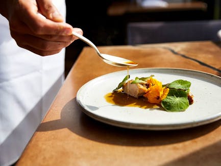 A chef finishes a dish of roasted guinea hen, purée of summer mushrooms and nasturtium, and hazelnut jus at Restaurant Pearl Morissette in Jordan Station, Ont.