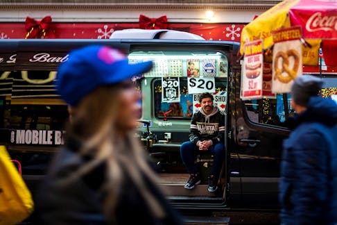 An independent barber waits for customers on his van in a local street in New York, U.S., December 25, 2023.