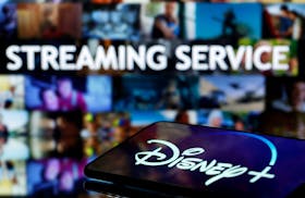 A martphone with displayed "Disney" logo is seen in front of displayed "Streaming service" words in this illustration taken March 24, 2020.