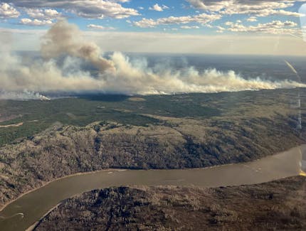 A picture taken through a window shows smoke rising from a wildfire on the south side of the Athabasca River valley near Fort McMurray, Alberta, Canada May 10, 2024. Alberta Wildfire/Handout via