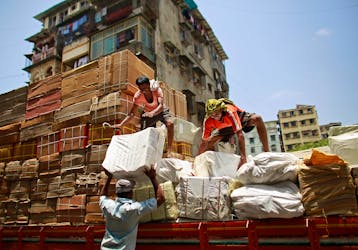 Workers of a transport company load packages on a truck at a wholesale market in Mumbai May 13, 2013. 