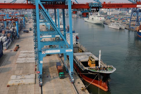 A crane loads containers onto a ship at the Tanjung Priok port in Jakarta, Indonesia, August 3, 2022.