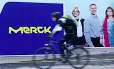A cyclist drives past a logo of drugs and chemicals group Merck KGaA in Darmstadt, Germany January 28, 2016. 