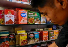 A man stands near the spice boxes of MDH and Everest kept on the shelf of a shop at a market in New Delhi, India, April 29, 2024.