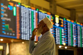 A stock broker reacts while monitoring the market on the electronic board displaying share prices during trading session at the Pakistan Stock Exchange, in Karachi, Pakistan July 3, 2023.