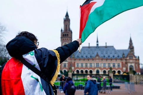 A man waves a Palestinian flag as people protest on the day of a public hearing held by The International Court of Justice (ICJ) to allow parties to give their views on the legal consequences of Israel's occupation of Palestinian territories before eventually issuing a non-binding legal opinion, in The Hague, Netherlands, February 21, 2024.