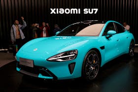 Visitors film around Xiaomi's first electric vehicle, the SU7, displayed at an event in Beijing, China December 28, 2023.