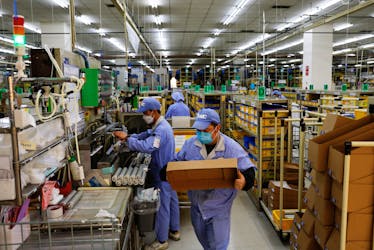 Employees work on a production line manufacturing mechanical parts, amid the coronavirus disease (COVID-19), at a factory of SMC Corporation, during an organised media tour, in Beijing, China January 10, 2023.