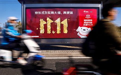 People ride on a scooter past a JD.com's advertisement promoting Singles Day shopping festival, in Beijing, China October 26, 2023.