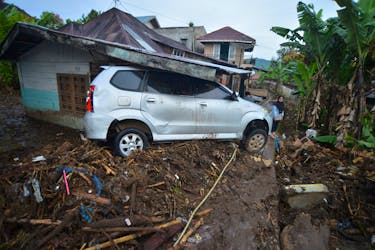 A woman stands near a damaged car in an area affected by heavy rain, which caused flash floods, in Agam, West Sumatra province, Indonesia, May 15, 2024, in this photo taken by Antara Foto. Antara Foto/Iggoy el Fitra/via REUTERS