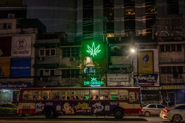 A bus drives past the neon sign of a cannabis shop in Bangkok, Thailand, August 18, 2023.