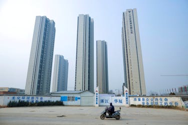 A man rides a scooter past apartment highrises that are under construction near the new stadium in Zhengzhou, Henan province, China, January 19, 2019.