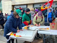 Striking PSAC workers write on picket signs in Ottawa on Wednesday, April 19, 2023.
