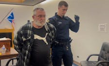 A sheriff's officer escorts Tony Humby, 62, from a provincial courtroom in St. John's during a break in Humby's bail hearing May 3, 2023.