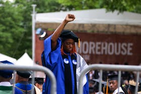 Taura Taylor, assistant professor of sociology at Morehouse College, stands with her back turned and holding up her fist during a speech by U.S. President Joe Biden, during a Morehouse College commencement ceremony in Atlanta, Georgia, U.S., May 19, 2024. 
