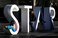 A tourist poses for pictures at the main sign of The Star Casino at Pyrmont Bay in Sydney, Australia, July 4, 2013.  