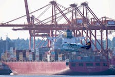 A float plane flies past containers and cranes at the Port of Vancouver, British Columbia, Canada, July 30, 2023.
