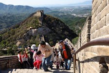 A woman helps a child to climb the stairs amid tourists visiting the Badaling section of the Great Wall, in Beijing, China October 1, 2023.