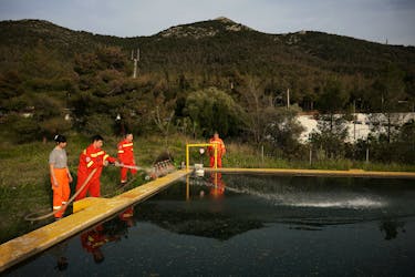 A volunteer pours water in a tank at a fire station in Hymettus mountain, in Athens, Greece, April 1, 2024.