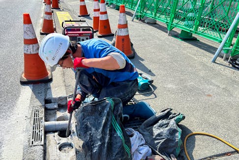 A construction worker digs a hole in the ground to build a black screen barrier on the other side of a road across a convenience store, which is known as a viral photo spot for taking pictures of Mount Fuji with the store, in Fujikawaguchiko town, Yamanashi prefecture, Japan May 2, 2024.