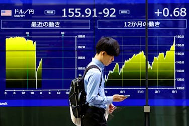 A man walks past an electronic screen displaying the current Japanese Yen exchange rate against the U.S. dollar and the graph showing its recent movement in Tokyo, Japan May 2, 2024,