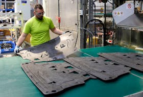 An employee holds an underfloor shield in production at a plant of Swiss car parts supplier Autoneum in Sevelen, Switzerland September 5, 2019. Picture taken September 5, 2019.