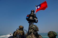 Members of Taiwan's Navy and media onboard a special operation boat with a Taiwanese flag fluttering over it during a drill part of a demonstration for the media, to show combat readiness ahead of the Lunar New Year holidays, on the waters near a military base in Kaohsiung, Taiwan January 31, 2024.