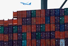 Shipping containers are seen stacked on a docked cargo ship as a passenger airplane takes off from Newark Airport, in Port Elizabeth, New Jersey, U.S., July 12, 2023.