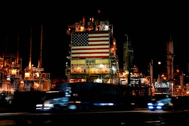Semi trucks drive past a giant U.S. flag displayed at Marathon Petroleum's Los Angeles Refinery in Carson, California, U.S., March 11, 2022. Picture taken March 11, 2022. Picture taken with long exposure.