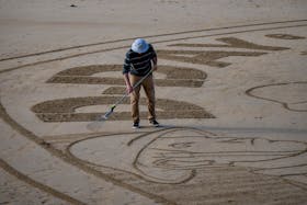French sand artist Jehan-Benjamin Tarain recreates a 50-pence coin design, created by David Lawrence to commemorate 80 years since D-Day landings during World War Two, on the beach which was codenamed 'Gold', in Normandy, France May 7, 2024 in this handout image. The Royal Mint/Handout via