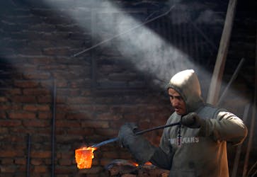 A worker carries a crucible of melted copper as he makes statues at a workshop in Lalitpur, Nepal December 23, 2015.