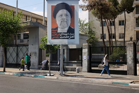People walk near a banner with a picture of the late Iran's President Ebrahim Raisi on a street in Tehran, Iran May 20, 2024. Majid Asgaripour/WANA (West Asia News Agency) via REUTERS