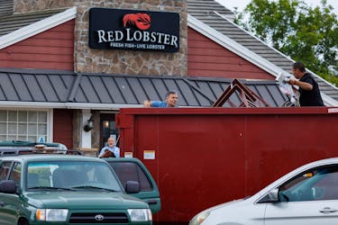 People collect items from a dumpster in front of a closed Red Lobster restaurant whose entire contents are up for auction in San Diego, California, U.S., May 15, 2024.  