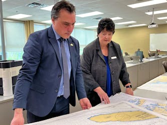 Shelburne County MLA Nolan Young and Mary Thompson, Principal, NSCC Burridge, Shelburne Campus and Digby Site look through the stack of nautical charts to be used with the new marine simulator at the school of fisheries at the NSCC Shelburne Campus. Kathy Johnson