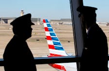Pilots talk as they look at the tail of an American Airlines aircraft at Dallas-Fort Worth International Airport February 14, 2013.