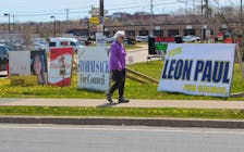 A passerby walks in front of several lawn signs from candidates running in Membertou's upcoming election. Voters in the Mi'kmaq community will go to the polls on June 13 to elect, or re-elect, its chief and council members. IAN NATHANSON/CAPE BRETON POST