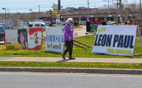 A passerby walks in front of several lawn signs from candidates running in Membertou's upcoming election. Voters in the Mi'kmaq community will go to the polls on June 13 to elect, or re-elect, its chief and council members. IAN NATHANSON/CAPE BRETON POST