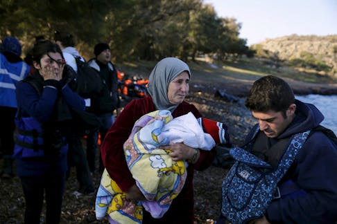 A Syrian refugee woman (C) cries as she holds a baby while refugees and migrants arrive on a boat on the Greek island of Lesbos, November 7, 2015. 
