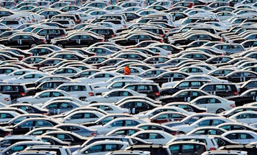 A worker walks along rolls of Mercedes cars at a shipping terminal in the harbor of the town of Bremerhaven, Germany, March 8, 2012.