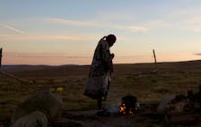 A woman warms water on an open fire near the home of former South African President Nelson Mandela's house in Qunu, June 28, 2013.