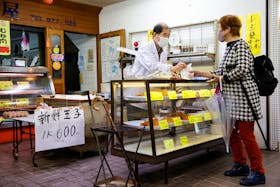 A customer buys food at a shop selling cooked food at a market in Tokyo, Japan, March 24, 2023.