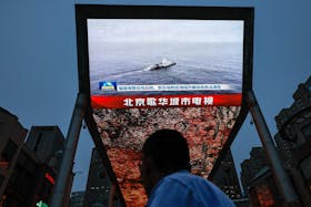 A person looks at a screen showing news footage of military drills conducted in areas around the island of Taiwan by the Eastern Theatre Command of the Chinese People's Liberation Army (PLA), in Beijing, China May 23, 2024.