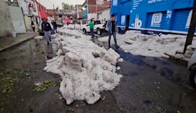 People walk next to thick ice following a hailstorm amid heat wave, in Puebla, Mexico May 24, 2024. REUTERS TV/Genaro Zepeda