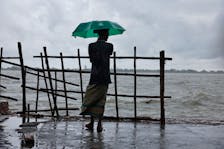 A man stands on the bank of Kholpetua river with an umbrella before the Cyclone Remal hits the country in the Shyamnagar area of Satkhira, Bangladesh, May 26, 2024.