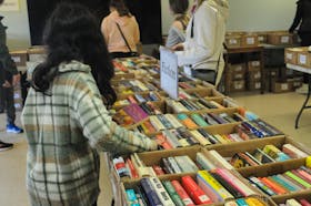 A young girls peruses through these fiction books while visiting the Friends of the St. John’s Public Library spring book sale with her guardians on Saturday, May 25, 2024, at the A.C. Hunter Public Library community room in the Arts & Culture Centre.
-Photo by Joe Gibbons/The Telegram