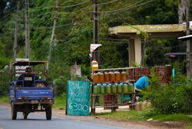 Containers with fuel are offered for sale on the side of the road near the border with Argentina, in Nanawa, Paraguay May 16, 2024. The sign shows prices for the different fuels on sale.