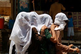 Men ride on a motorbike as they cover their heads with a wet cloth to cool off and to avoid sunlight, during a hot summer day, as the heatwave continues in Jacobabad, Pakistan May 26, 2024.