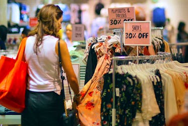 A shopper touches a dress as she inspects clothes on display next to sale signs at a retail store in central Sydney, Australia, October 25, 2017.    