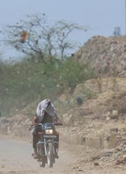A man rides his bike near a landfill site on a hot summer day during a heatwave in New Delhi, India, May 27, 2024.